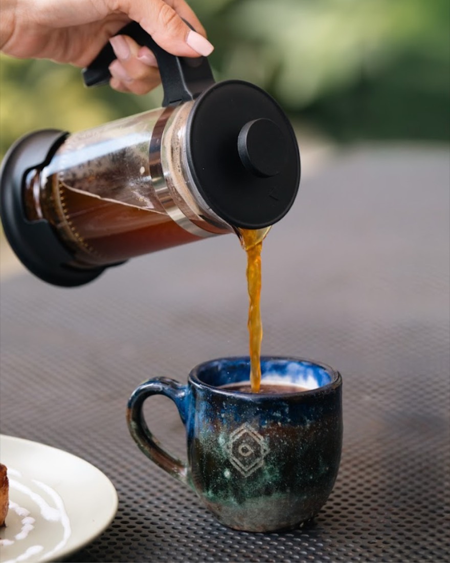 Café servido de una prensa francesa a una taza de cerámica azul